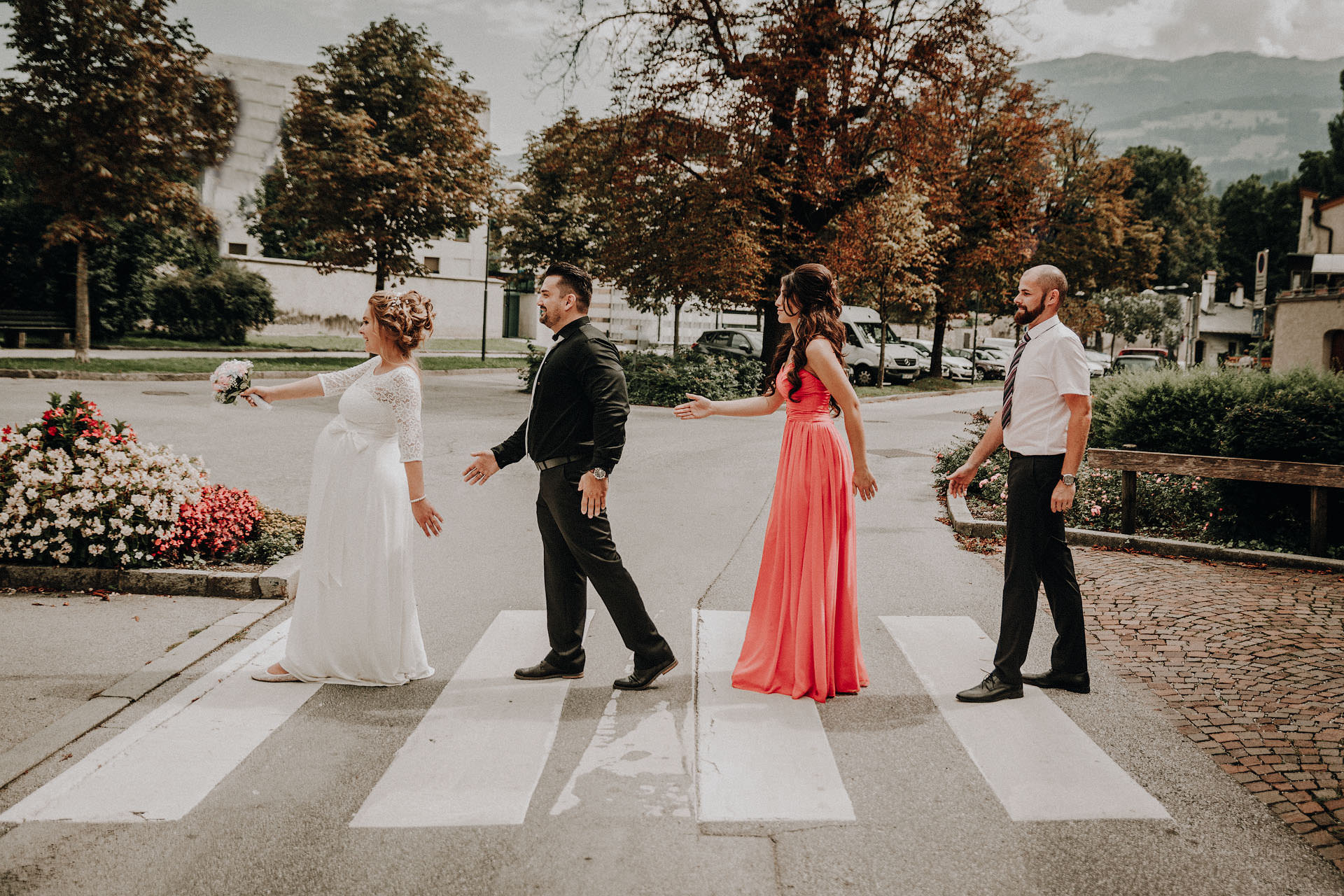 Hochzeitspaar und Trauzeugen stellen das berühmte Bild der Beatles (The Beatles) auf dem Zebrasteifen der Abbey Road in London, England in Hall in Tirol nach